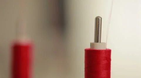 Sewing bobbin being wound up on a sewing machine with red thread. Stock Footage 58052295