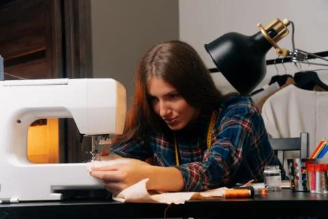 The sewing designer sews on a sewing machine. The concept of a small home Stock Photos