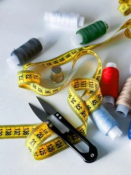 Sewing essentials. Measuring tape, threads, scissors, and thimble for tailoring Stock Photos