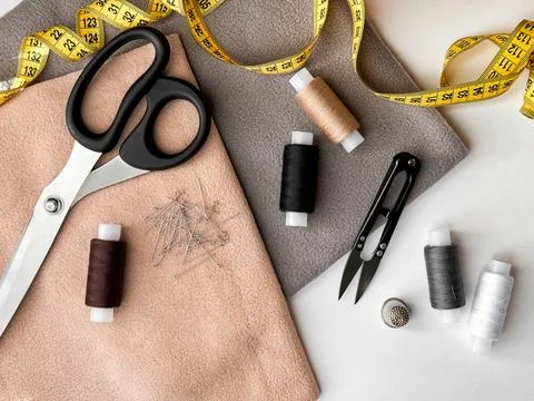 Sewing essentials with scissors, measuring tape, and thread on fabric Stock Photos