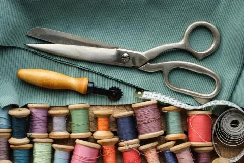 Sewing items: retro tailoring scissors, measuring tape, threads. Stock Photos