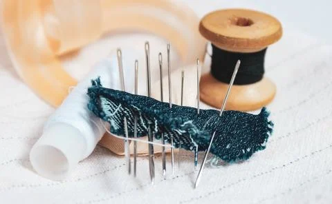 A sewing kit made of thread, a set of needles and a slanting label on the tab Stock Photos