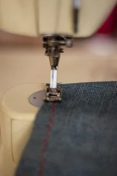 Sewing machine close up sewing blue jeans denim. Stock Photos