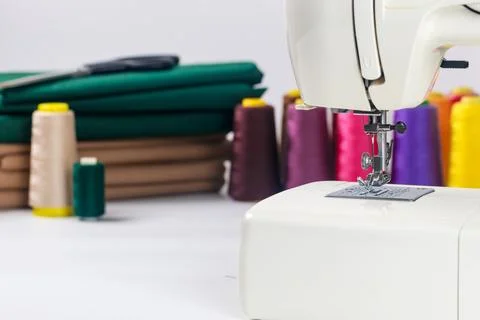 Sewing machine with colorful thread spools and fabric in bright crafting space Stock Photos