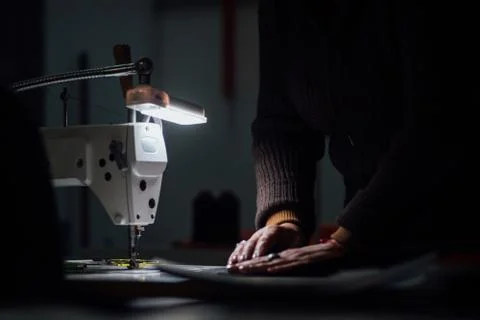 Sewing machine in dark with working hands on backdrop Foto stock