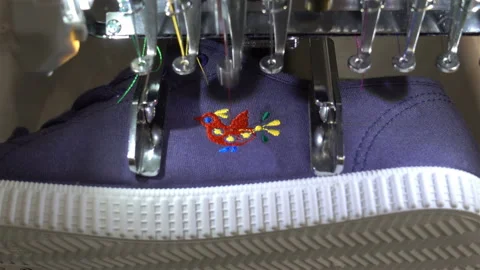 A sewing machine embroiders a pattern on sneakers in 4K Stock Footage 116338418