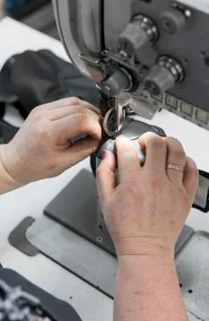 Sewing machine in a leather workshop in action with hands working on a leather Stock Photos