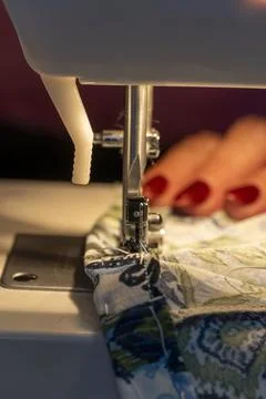 Sewing machine needle in foreground with woman's hands out of focus in back.. 스톡 사진