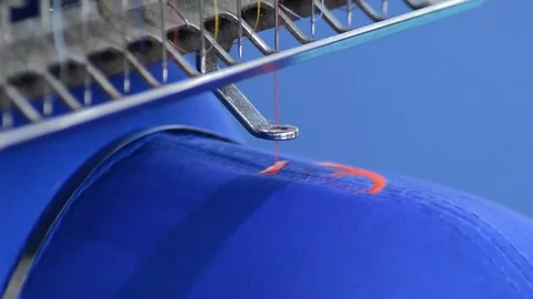 Sewing machine needle knitting a blue cap with red thread Stock Footage 89985400