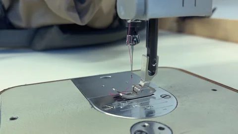 Sewing machine needle in motion stitching fabric on work surface with tools Stock Footage 346494496