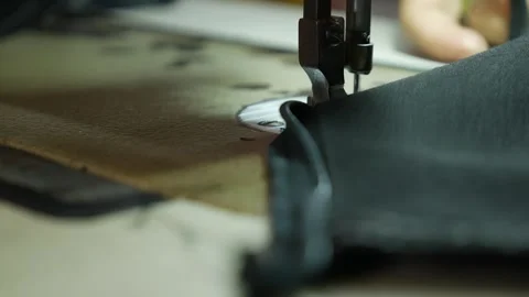 A sewing machine needle moves through fabric during stitching on a work table in Stock Footage 339279822