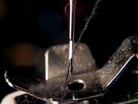 A sewing machine needle precisely holds thread, ready for stitching in a di.. Stock Photos