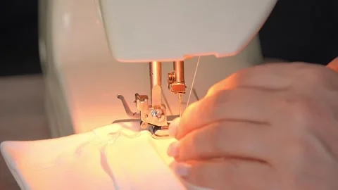 Sewing machine needle repeatedly pierces blue fabric in slow motion 库存影片 311993512