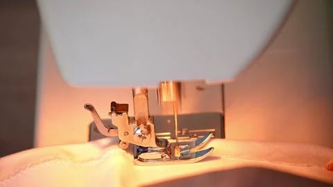 Sewing machine needle repeatedly pierces blue fabric in slow motion Stock Footage 311993772