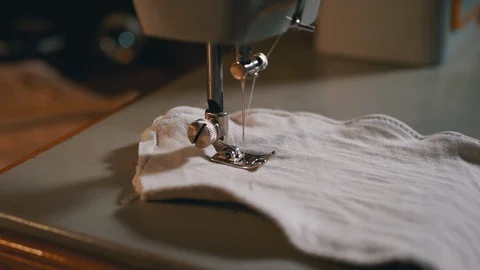 Sewing Machine Needle in Slow Motion. A Tailor Sews Homemade Face Mask of Fabric Stock Footage 127867228