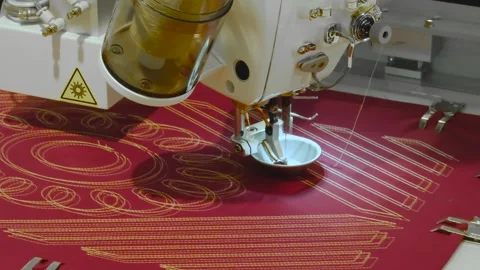 Sewing machine needle stitches red fabric with gold geometric patterns. Close Stock Footage 337628618