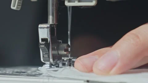 Sewing machine needle stitching white fabric with hand holding material Stock Footage 314644336
