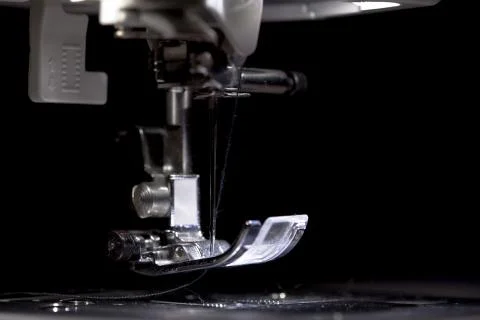 Sewing machine part with needle closeup on black background Stock Photos