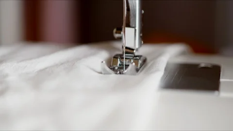 Sewing machine sews white fabric with white thread. Slow action, the needle of Stock Footage 128388696