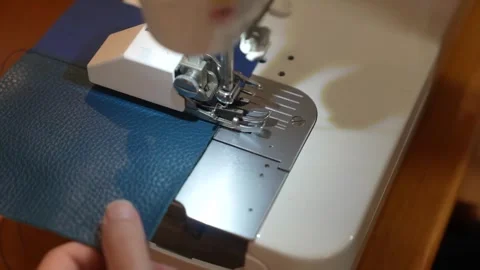 Sewing machine stitches edge of textured blue leather panel Stock Footage 339642833