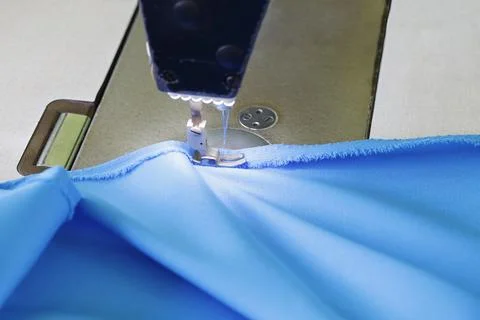 Sewing machine stitching blue fabric, showcasing garment production, textil.. Stock Photos