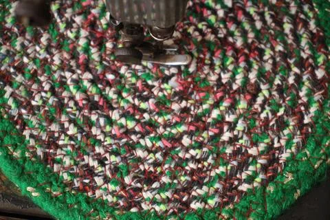 A sewing machine is stitching a multicoloured mat. Fotos de archivo