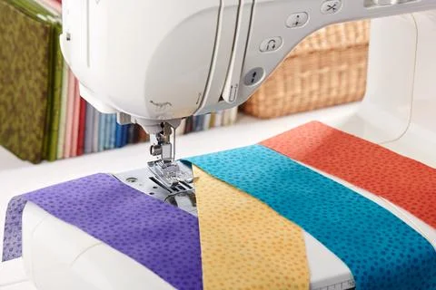 Sewing machine with a strips of fabrics on the background of stack of color.. 스톡 사진