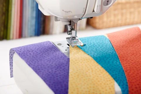 Sewing machine with a strips of fabrics on the background of stack of color.. Fotos de archivo