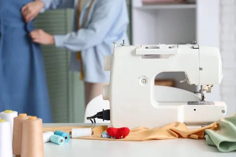 Sewing machine on table against female tailor working in atelier Stock Photos