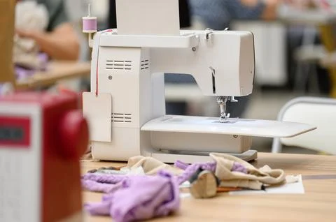 Sewing machine on table with fabric pieces and tools in workshop setting Stock Photos