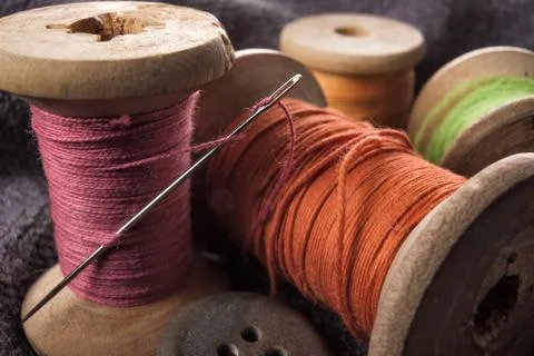 Sewing needle and cotton thread on wooden spool macro view. Stock Photos
