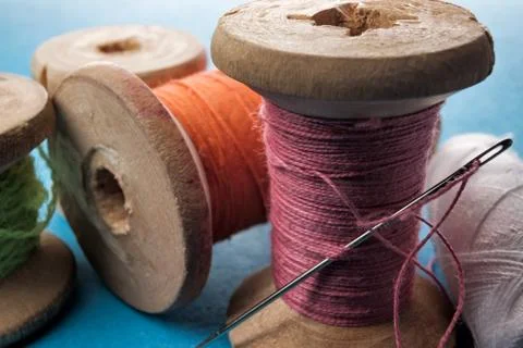 Sewing needle and cotton thread on wooden spool macro view. Stock Photos