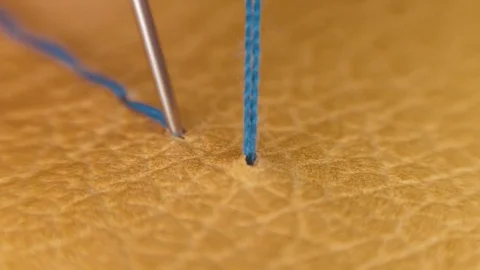 Sewing needle with a blue thread makes a line on the yellow natural skin Video stock 82694403