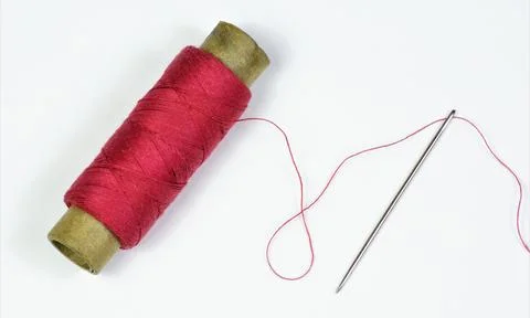 The sewing needle is a pointed tool and a red thread threaded. Stock Photos