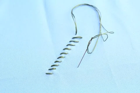 Sewing needle with thread and stitches on light blue cloth, closeup 写真素材