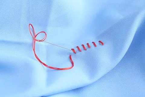 Sewing needle with thread and stitches on light blue cloth, closeup Stock Photos