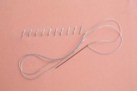 Sewing needle with thread and stitches on coral cloth, top view Stock Photos