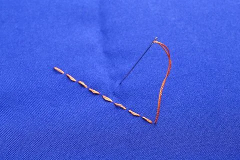 Sewing needle with thread and stitches on blue cloth, closeup 写真素材