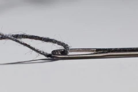 Sewing needle with thread inside on the table macro photo blurred background Stock Photos