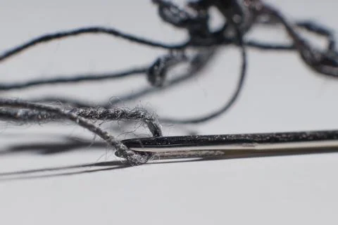 Sewing needle with thread inside on the table macro photo blurred background Stock Photos