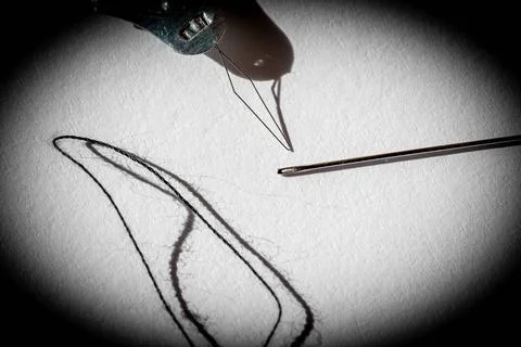 Sewing needle threader tool in use and a single black string. Sewing needl... Stock Photos