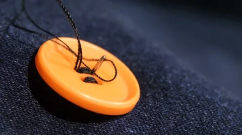 Sewing an orange button on jeans, denim, close up Stock Footage 49473858