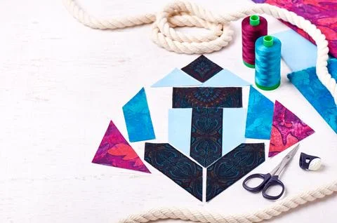 Sewing patchwork of block anchor, spools of threads, fabrics, rope lie on w.. Stock Photos