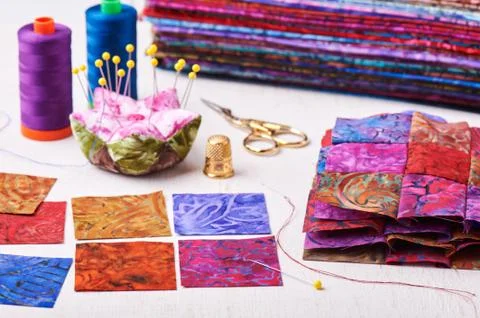 Sewing patchwork blocks to colorful batik quilt Stock Photos
