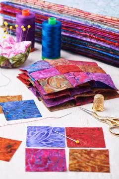Sewing patchwork blocks to colorful batik quilt Stock Photos