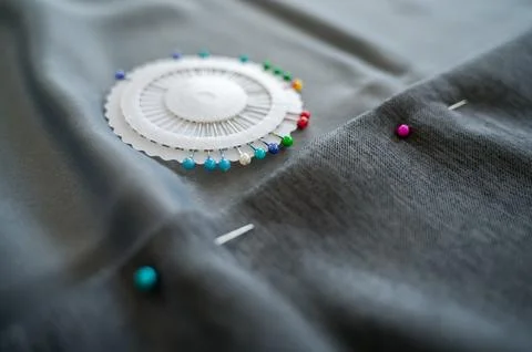 Sewing pins are lying in case on fabric being hemmed Stock Photos