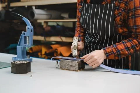 Sewing process. Cropped view of the tailor making holes for the buckle on bag Foto stock
