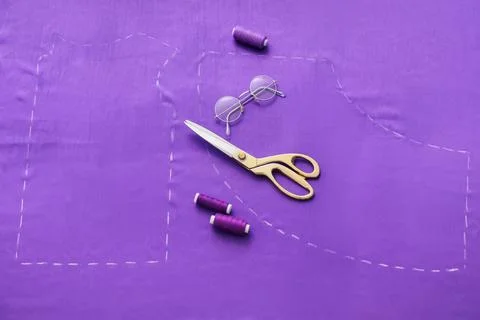 Sewing project preparation with golden scissors, purple thread spools, and ey Stock Photos
