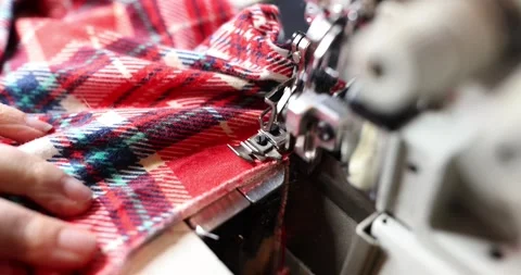 Sewing a red and green checkered flannel shirt using a sewing machine Stock Footage 281246778