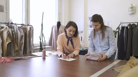 In sewing studio tailor on paper explains to courier where to deliver product. Video stock 88484072